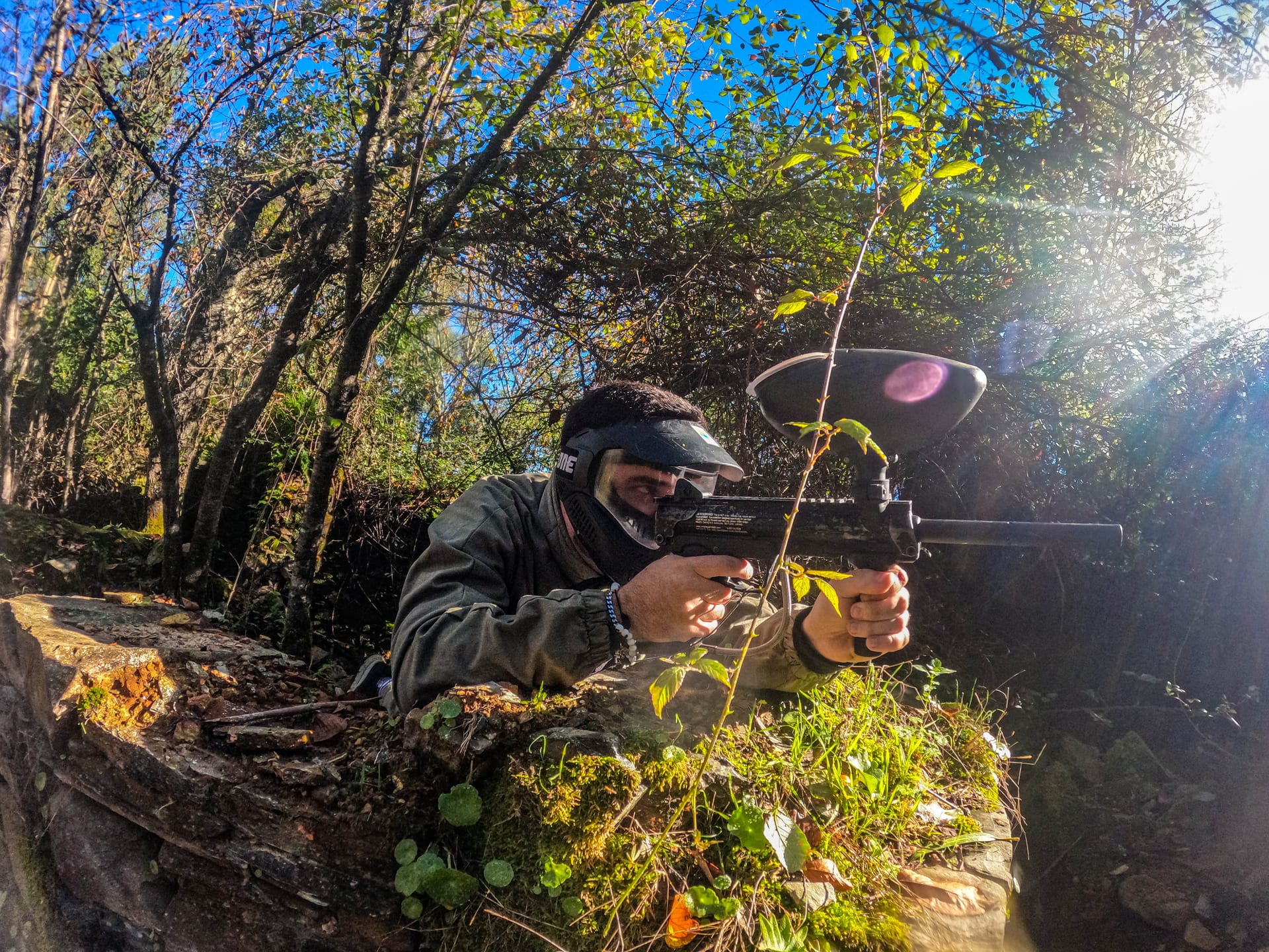 Jogador de paintball protegido e apontado entre a vegetação